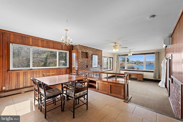 dining space with wooden walls, a water view, an AC wall unit, light tile patterned flooring, and a notable chandelier