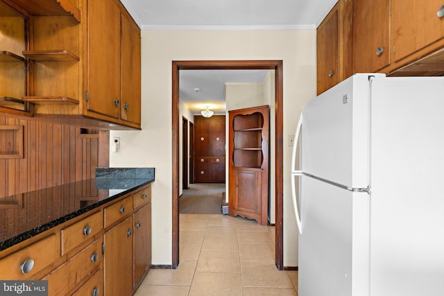 kitchen with light tile patterned floors, brown cabinets, freestanding refrigerator, and open shelves