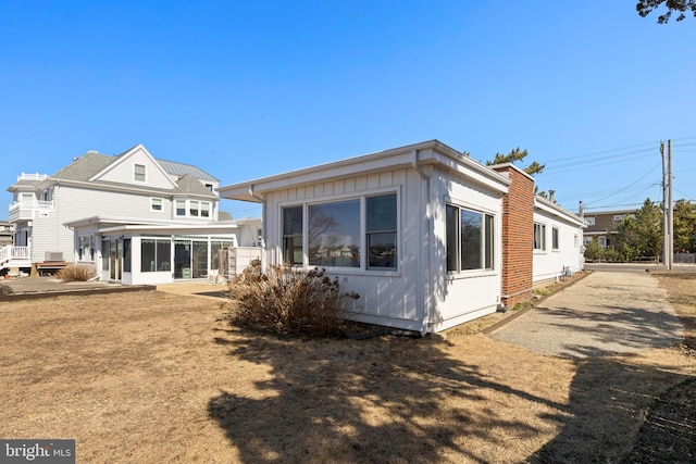 rear view of house with board and batten siding and a sunroom