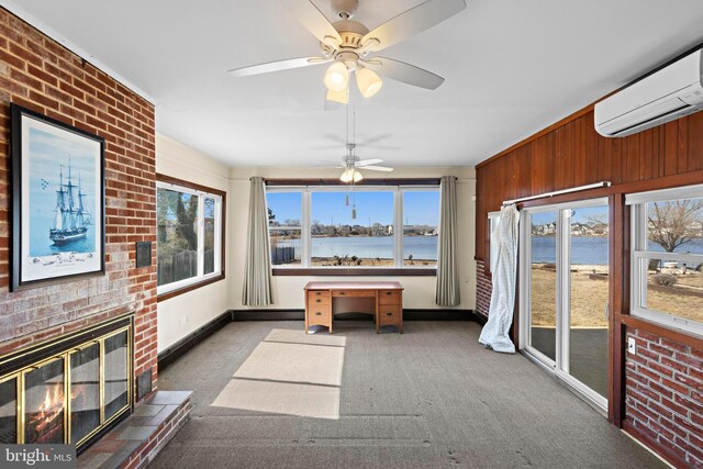 unfurnished sunroom featuring a wall mounted air conditioner, a water view, and a fireplace