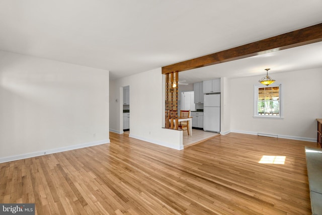 unfurnished living room with beam ceiling, baseboards, light wood-type flooring, and a baseboard radiator