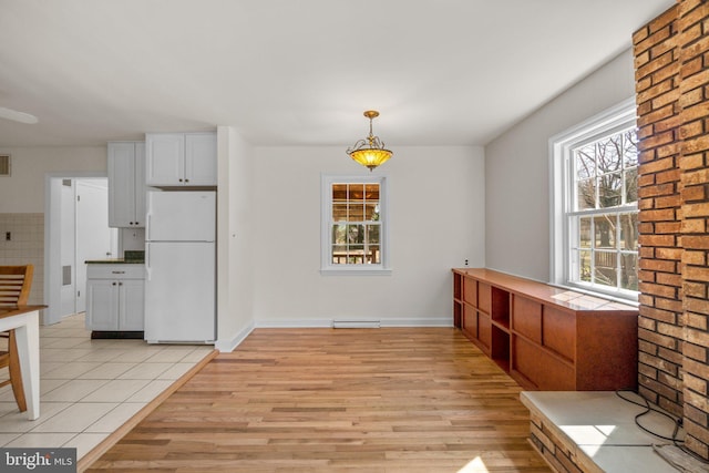 unfurnished dining area featuring baseboards and light wood-style flooring