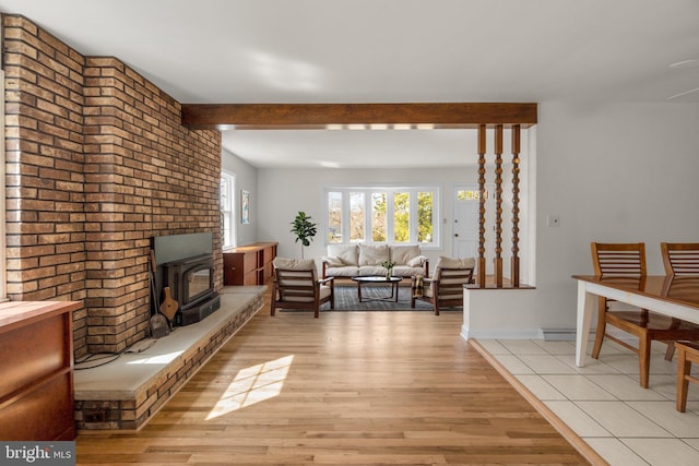 living room with beam ceiling, a wood stove, and light wood-style floors