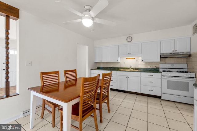 kitchen featuring under cabinet range hood, a sink, tasteful backsplash, dark countertops, and white range with gas stovetop