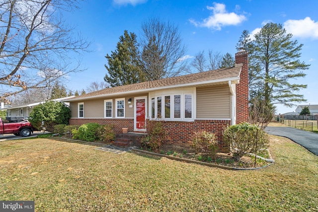 ranch-style house with brick siding, a chimney, and a front lawn