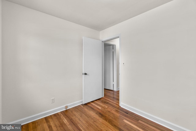 spare room featuring baseboards and wood finished floors