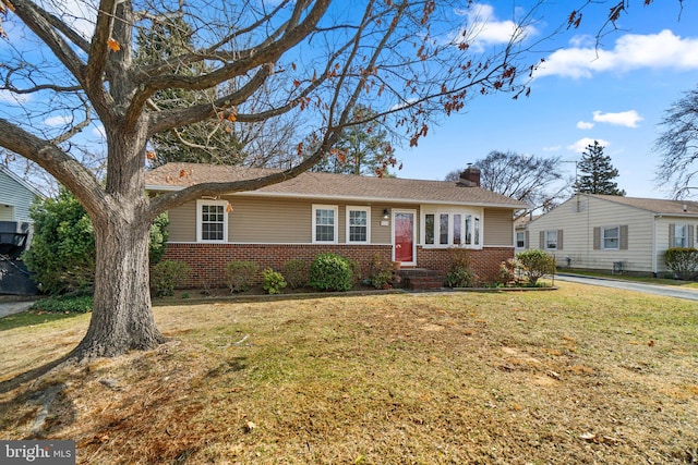 ranch-style house with brick siding, a chimney, and a front lawn