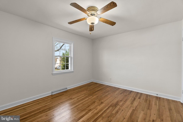 unfurnished room featuring a baseboard heating unit, a ceiling fan, baseboards, and wood-type flooring