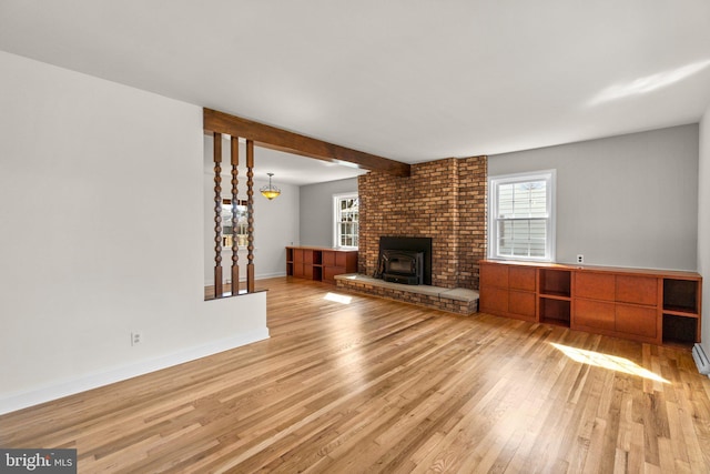 unfurnished living room with beam ceiling, baseboards, and wood finished floors