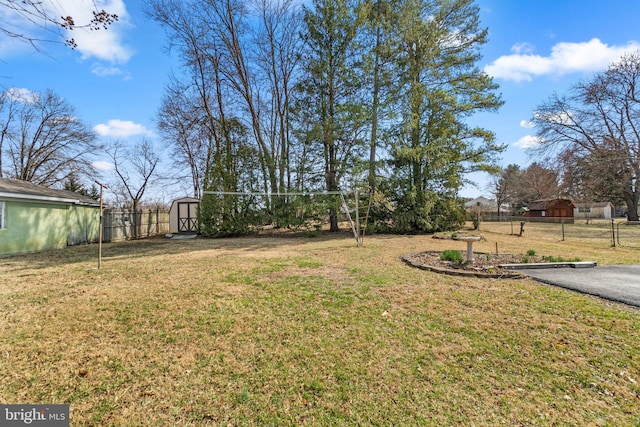 view of yard with a storage shed, an outdoor structure, and fence