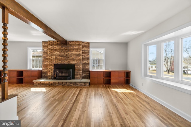 unfurnished living room with beam ceiling, a healthy amount of sunlight, baseboards, and light wood-style floors