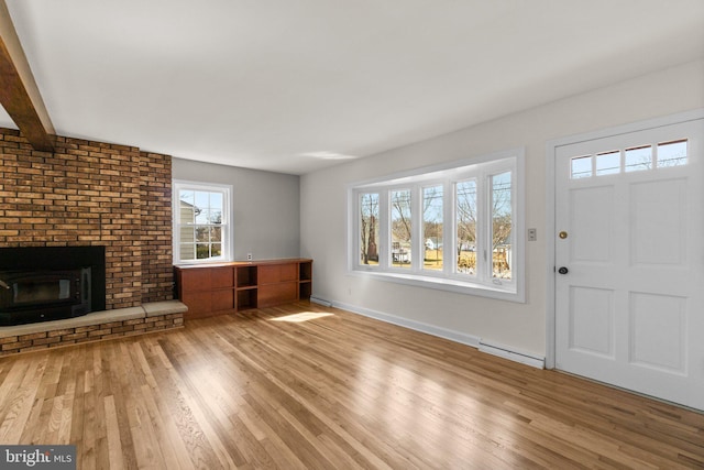 unfurnished living room with wood finished floors, baseboards, a fireplace, a baseboard heating unit, and beamed ceiling