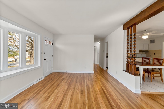 interior space with a baseboard radiator, baseboards, visible vents, and light wood-type flooring