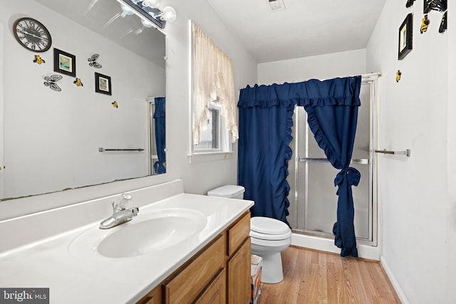 full bath with a stall shower, toilet, vanity, and wood finished floors