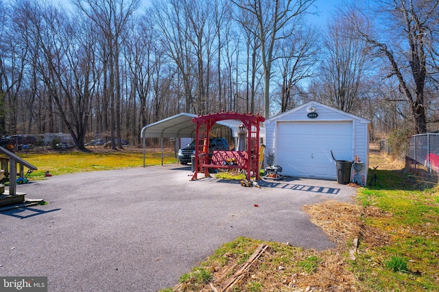 detached garage featuring a carport, fence, and driveway