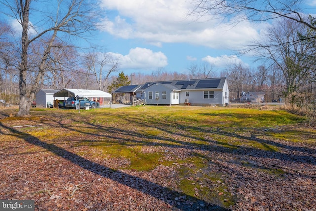 exterior space with a detached carport, a lawn, and roof mounted solar panels