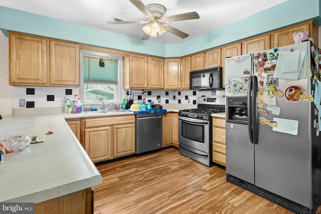 kitchen with a sink, appliances with stainless steel finishes, light countertops, and light wood finished floors