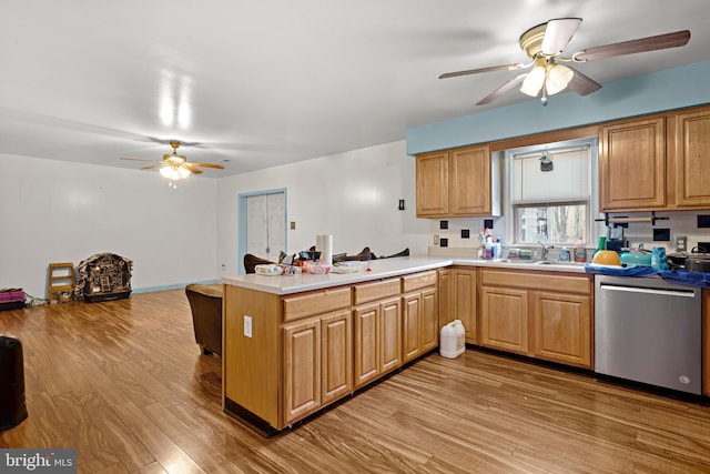 kitchen with dishwasher, light countertops, light wood-type flooring, a peninsula, and a sink