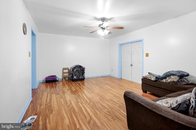 living area featuring a ceiling fan, baseboards, and light wood-type flooring