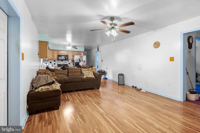 living room with a ceiling fan, baseboards, and light wood finished floors