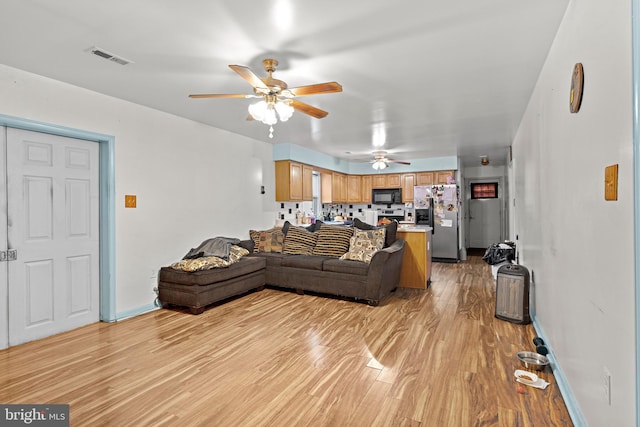 living room with visible vents, baseboards, ceiling fan, and light wood finished floors