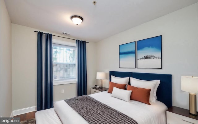 bedroom featuring wood finished floors, visible vents, and baseboards