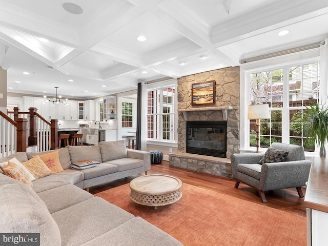 living room with a wealth of natural light, a fireplace, beamed ceiling, and wood finished floors