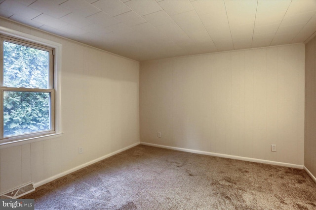 empty room featuring a healthy amount of sunlight, carpet, visible vents, and baseboards