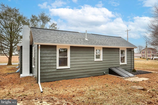 back of house with roof with shingles