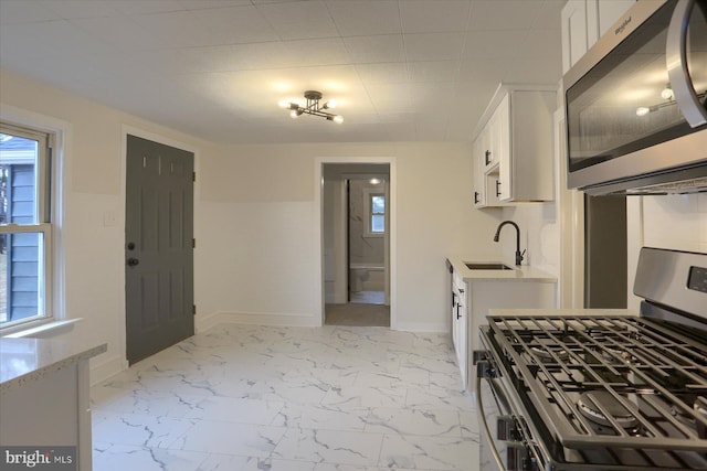 kitchen featuring marble finish floor, white cabinetry, stainless steel appliances, and a sink