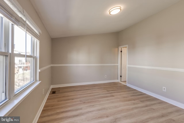 empty room featuring visible vents, baseboards, and light wood finished floors