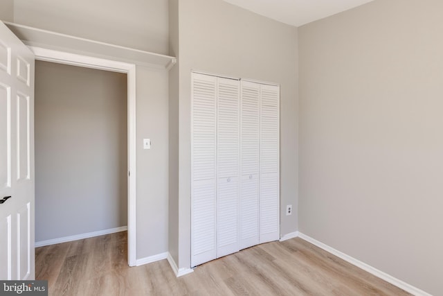 unfurnished bedroom featuring a closet, baseboards, and wood finished floors