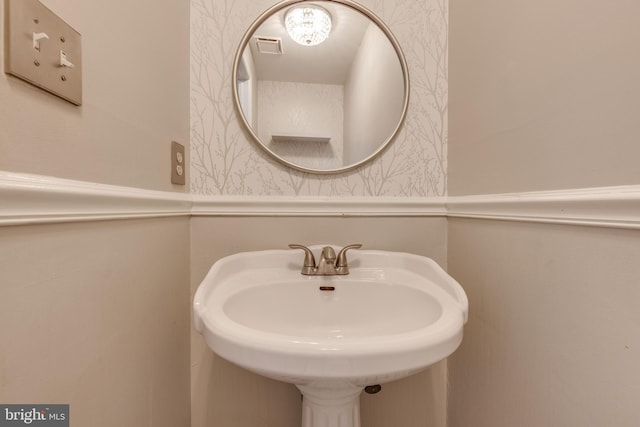 bathroom with wallpapered walls and a sink