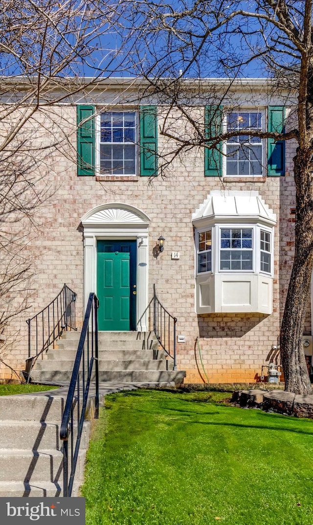 entrance to property featuring brick siding and a lawn