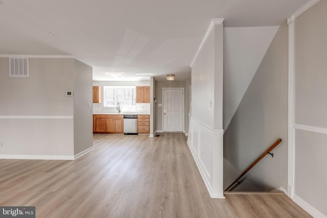 unfurnished living room featuring light wood finished floors, visible vents, crown molding, and a sink