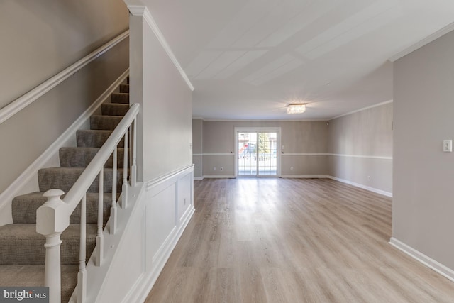 interior space with wood finished floors, ornamental molding, wainscoting, and a decorative wall