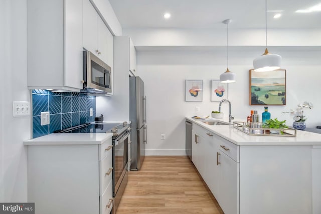 kitchen featuring backsplash, a peninsula, stainless steel appliances, light wood-type flooring, and a sink