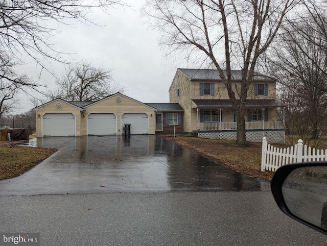 view of front of property featuring an attached garage, covered porch, fence, and aphalt driveway