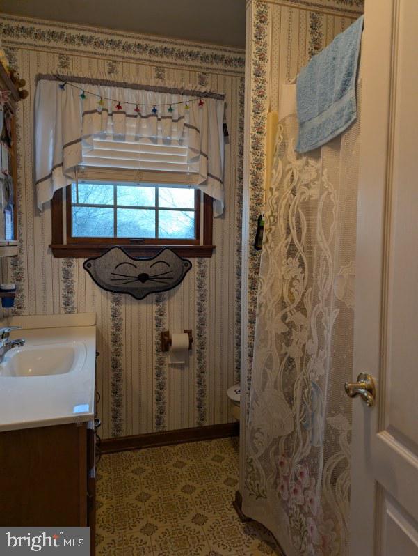 bathroom with toilet, tile patterned floors, vanity, and wallpapered walls