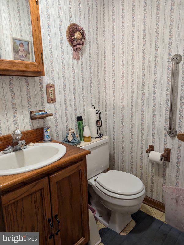 bathroom with tile patterned floors, vanity, toilet, and wallpapered walls