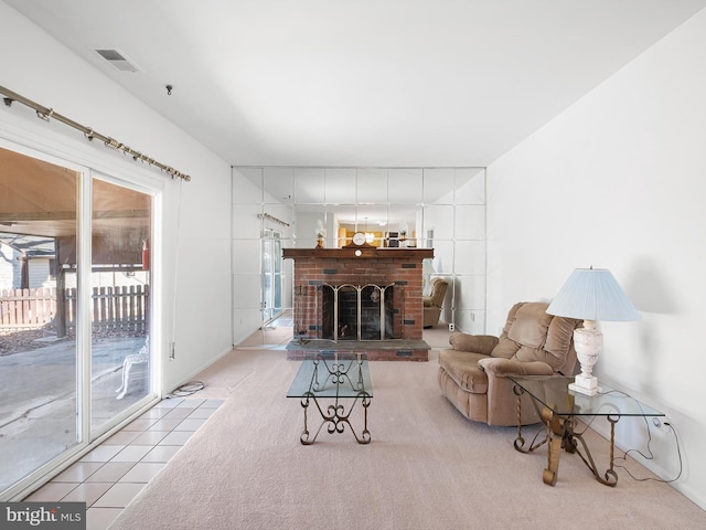 tiled living area with a brick fireplace, carpet flooring, and visible vents