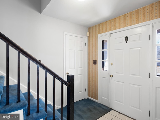 carpeted entryway with wallpapered walls and stairs