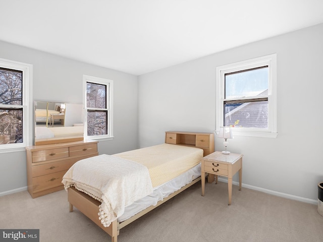 bedroom with multiple windows, light carpet, and baseboards