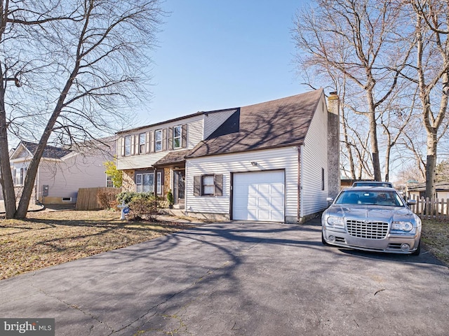 view of front of property featuring a garage, a chimney, fence, and aphalt driveway