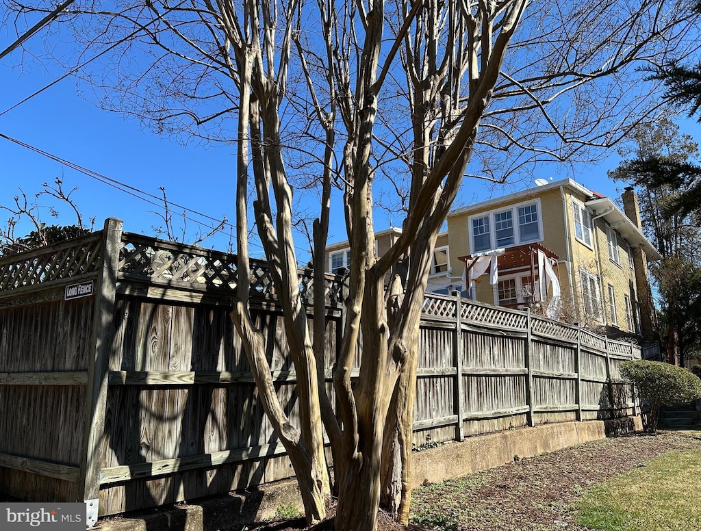 view of side of home featuring a chimney and fence