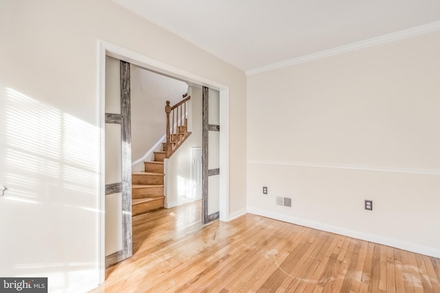 spare room with light wood finished floors, visible vents, stairway, ornamental molding, and baseboards