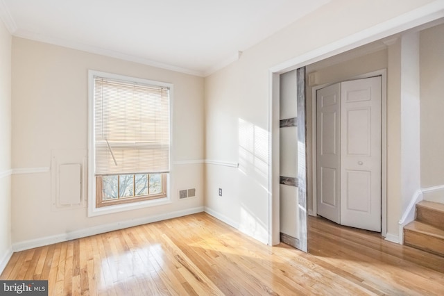 unfurnished room featuring ornamental molding, light wood finished floors, visible vents, and baseboards