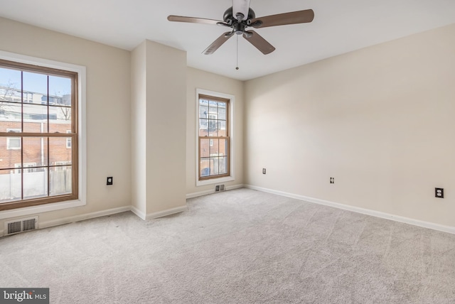 carpeted empty room featuring baseboards, visible vents, and a ceiling fan