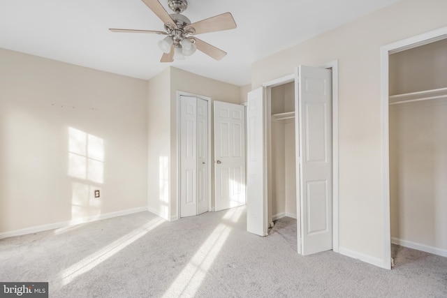 unfurnished bedroom featuring ceiling fan, carpet floors, two closets, and baseboards