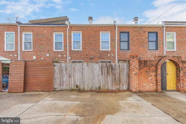 back of house featuring fence and brick siding